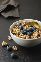 Granola with blueberry in white bowl.