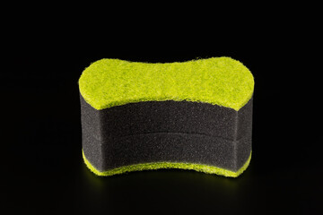Two black sponges with an abrasive bright green layer for washing dishes and other household or domestic needs. Isolated on black background