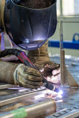 Worker With Welding Helmet And Protective Workwear Welding Train Construction. Portrait Of Welder With Torch At The Train Factory. 