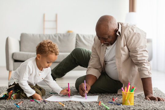 African American Grandpa And Grandson Sketching Sitting On Floor Indoors