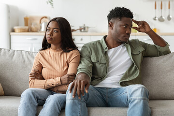 Upset african american couple sitting on couch at home