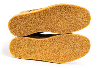 non-slip outsoles of two brown leather winter boots on a white background