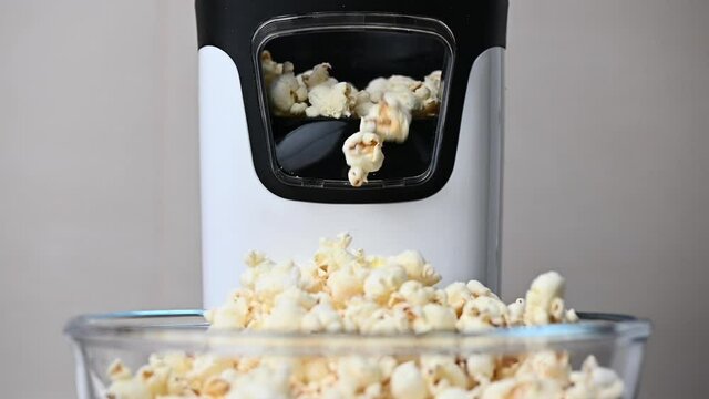 Slow motion video of popcorn machine producing popcorn out into bowl