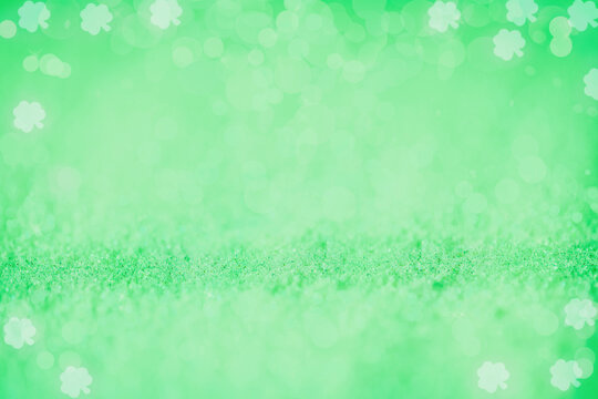 Beautiful bright blurred green glitter bokeh background with shamrock designs perfect for St. Patrick's Day. 