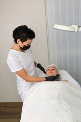 The beautician examines the patient before the facial treatment.