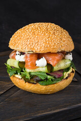 Fresh burger with pieces of salmon fish and vegetables.