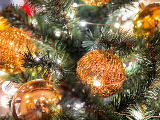 Christmas tree with shiny decorations. Fir tree decorated with golden ornamental glass balls for New Year celebration.