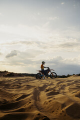 Motorcross riding over sand in desert dune