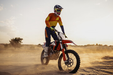 Motocross rider on sportmotor over dust landscape