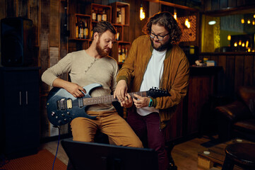 Musician teaching male student to play guitar