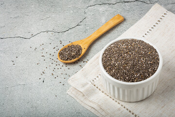 Chia seeds in bowl and wooden spoon on the table.