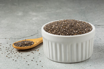 Chia seeds in bowl and wooden spoon on the table.