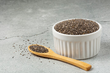Chia seeds in bowl and wooden spoon on the table.