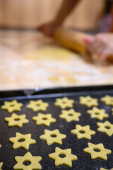 Glued stars on a plate and the hands of a woman rolling out the dough in the background.