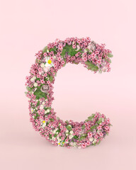 Creative letter Cconcept made of frash Spring wedding flowers. Flower font concept on pastel pink background.