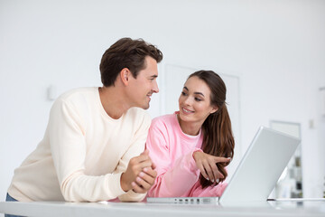 Fototapeta premium Happy young couple using laptop at home together.