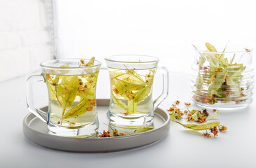 Closeup detail view two cups of linden tea with linden leaf in studio.