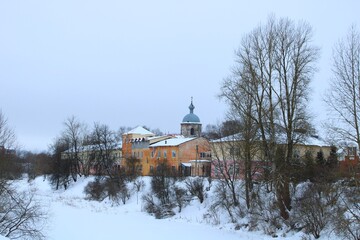 old small stone colorful houses on the city street in snow at winter and church on the hill