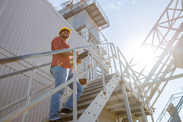 Happy African engineer standing at industrial site