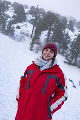 Fototapeta premium Portrait of happy teenage girl smiling and dressed in warm red coat at snow in winter