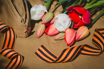 Banner for May 9. Military uniform, cap with a star, St. George ribbon and red tulips in the...