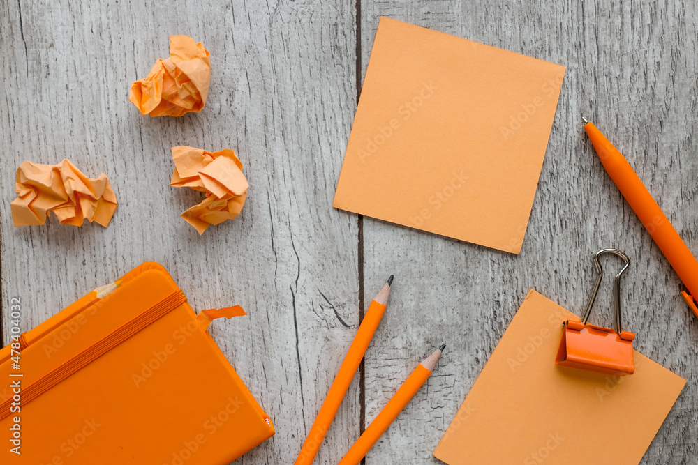 Poster orange pen for notepad and colorful notes on background, orange torn note paper on wood background. 