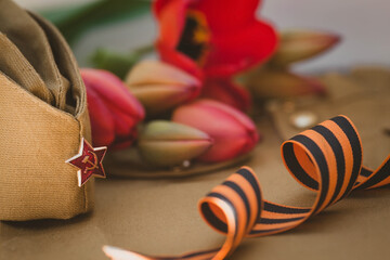 Banner for May 9. Military uniform, cap with a star, St. George ribbon and red tulips in the...