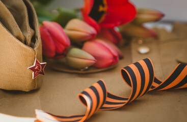 Banner for May 9. Military uniform, cap with a star, St. George ribbon and red tulips in the...