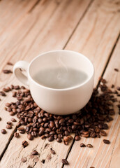 white cup of coffee with smoke on rustic wooden table, with roasted coffee beans.