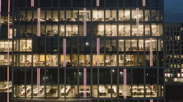 Cinematic aerial view of the offices at night in a business center. Close-up aerial view of the skyscraper and offices at night, panorama to the right