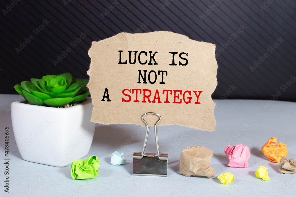 Poster luck is not a strategy text on a notebook on office desk.