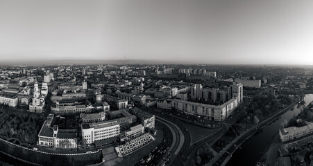 Grayscale panoramic aerial view above river Lopan embankment with Skver Strilka in Kharkiv, Ukraine. Wide cityscape - Pavlivska Square, Dormition Cathedral, city streets