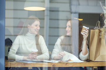 Two young women sitting at table in cafe. Teamwork, business meeting. Freelancers work.