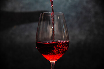 Glass of red wine in half on a dark background.