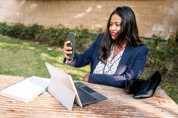 Businesswoman working outdoors with her laptop and smartphone