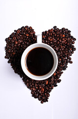 Heart shaped coffee beans with a cup of coffee in the center.