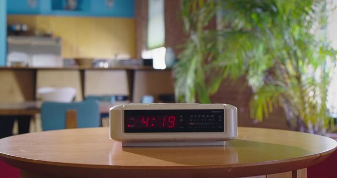 Detail of vintage digital alarm clock sitting on side table as time passes from 4:19 to 4:20 