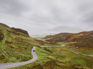 Small narrow road in a stunning mountain area. Mamore gap, county Donegal, Ireland. Amazing drive with rough wild nature scenery. Travel and tourism concept.