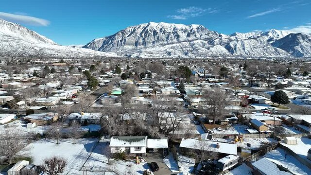 Drone flying toward beautiful snowy mountain above a snow covered city in the winter