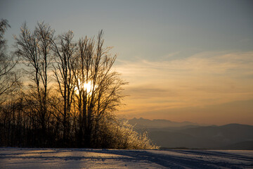 Fototapeta na wymiar a winter mountain glade in the background the setting sun, mountain mood, Beskid Sądecki