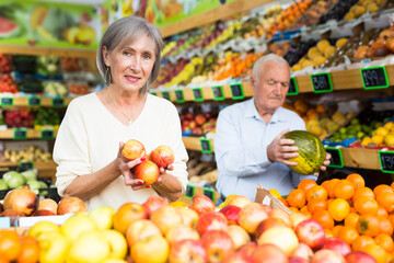 Portrait of Married couple buying apples and watermelon at grocery shop
