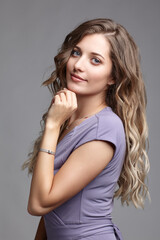 Studio portrait of a young woman in a summer dress. Blond female in a summer dress posing on gray background.