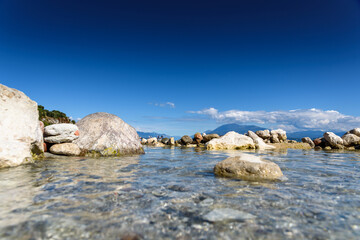 The tide covers the rocks on the shore of a crystal clear lake.