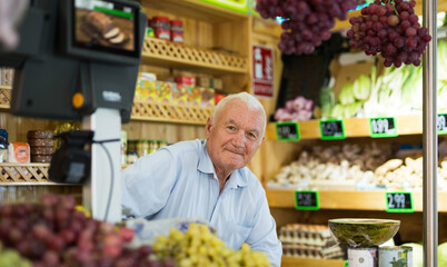 Portrait of a positive male salesperson at the checkout counter at a grocery supermarket