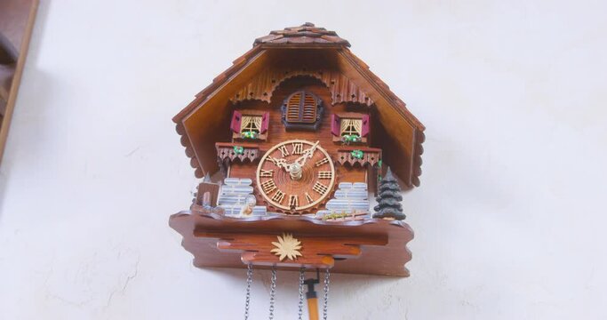 Pendulum starts working on vintage authentic wooden cuckoo clock with automated cuckoo bird that have to move with each note, hanging on wall at home, view from below.