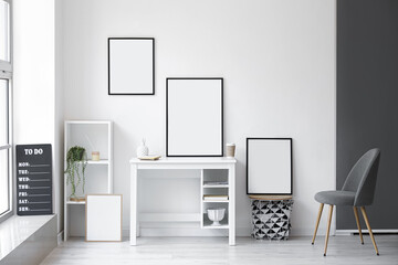 Interior of light room with modern workplace and blank frames
