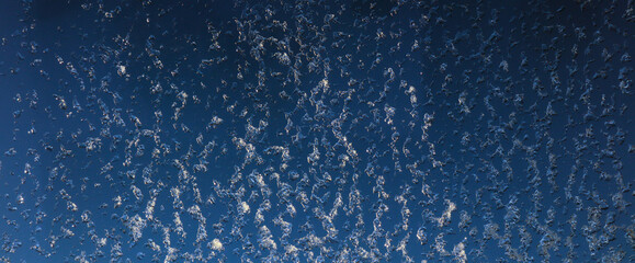 Frozen water on a window. Backdrop in blue.