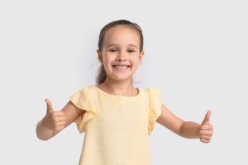 Funny little girl showing thumbs-up on white background