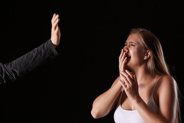 Man beating scared woman on dark background. Violence concept