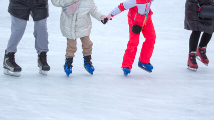 feet of different people skating on the ice rink